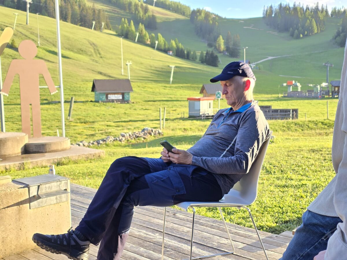 Ein Mann mit Schirmkappe sitzt nachdenklich auf der Terrasse in einem Stuhl in der Natur