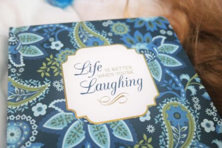 Buchcover mit blauen Blumen und dem Titel: Life ist better with laughing