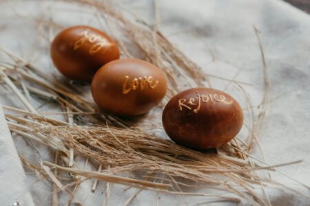 drei braune Ostereier im Stroh beschriftet mit: Joy, Love, Rejoce
