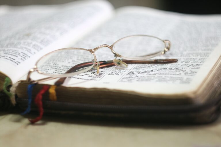 Bibel aufgeschlagen mit einer Lesebrille darauf.