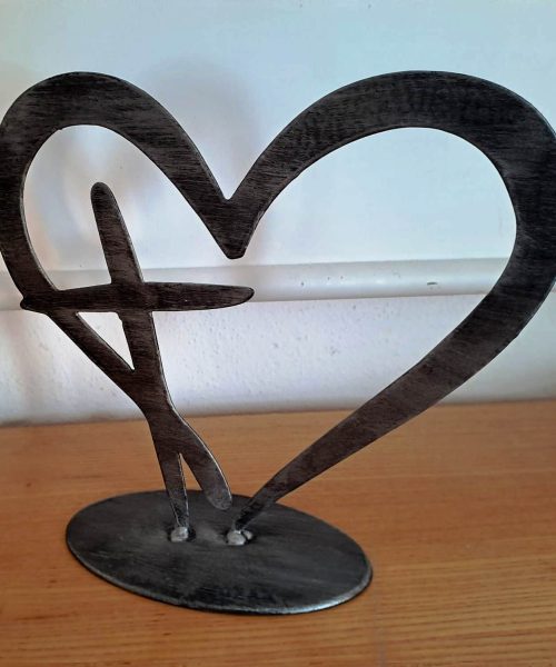 Skulptur eines Herzens mit Kreuz integriert aus Metall.