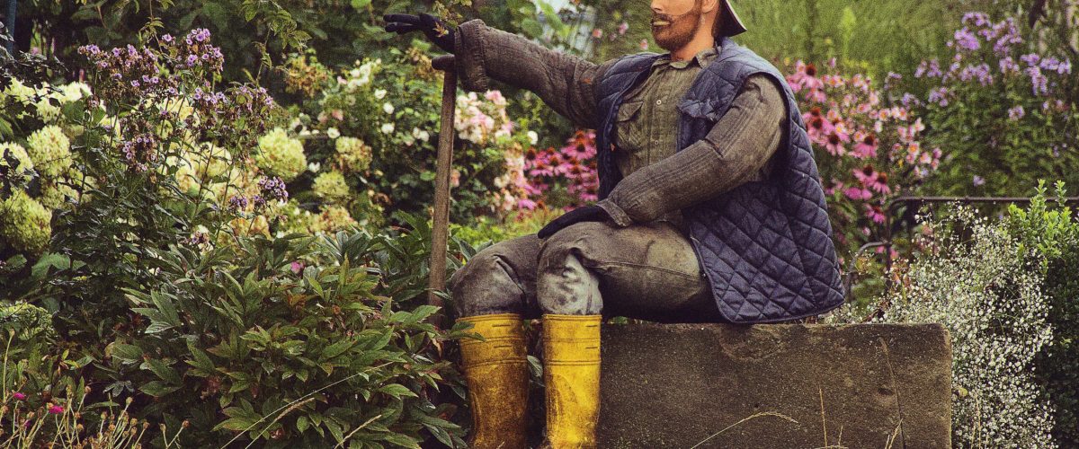 Frühlingsgarten mit einer Holzfigur, die als Gärtner gekleidet ist.